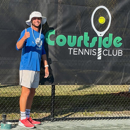 Courtside Tennis Club, Venice, Florida - logo on court fence with player in blue shirt